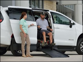 Man using wheelchair exiting accessible minivan on a ramp