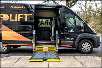 A yellow and black van parked in a parking lot with lift deployed.