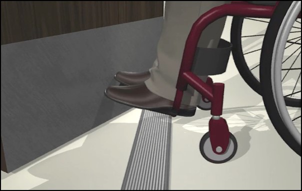 Detail of wheelchair user’s feet and footrests at open door with kickplate