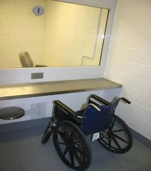 Detainee visitor area with wall-mounted seat that adjusts to allow room for a wheelchair 