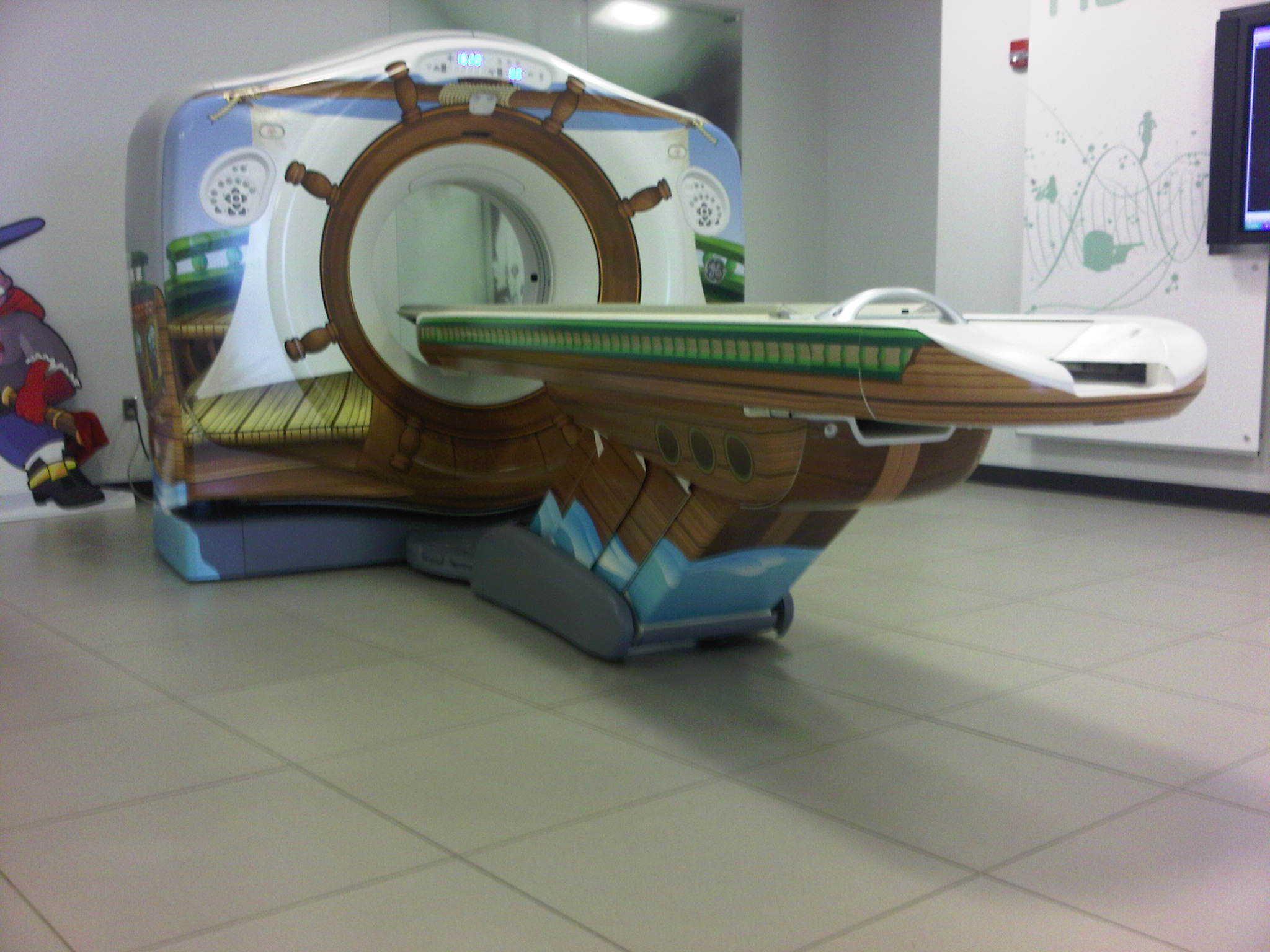 This is picture of a CT system (this one has decals on it for use in a children's hospital).  It is also representative of a MR table.  The table on this particular model is 7+ ft long, about 24 inches wide, and has a minimum height of about 18 inches.  Note the emergency extraction handle at the foot end of the table.  Also note that there is not structural material under the table side covers where transfer supports could sufficiently be anchored.