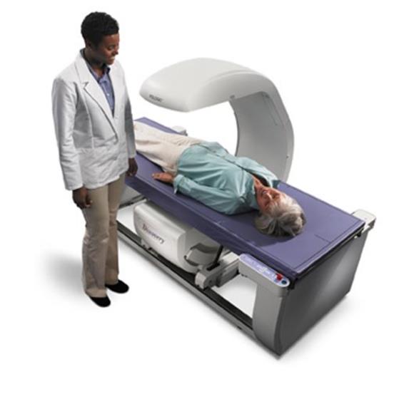 Picture shows a Dual Energy X-ray Absorptiometry (DXA) system for Osteoporosis assessment with a patient lying on the scanning bed.  A technician is standing beside the equipment. The table heights are fixed due to the diagnostic need for a fixed geometry. The table heights are typically 25 - 28 inches and are dictated by the needing the X-Ray source below the table for diagnostic and radiation dose considerations.  Also note the equipment imaging components on the opposite side of where the patient transfers.