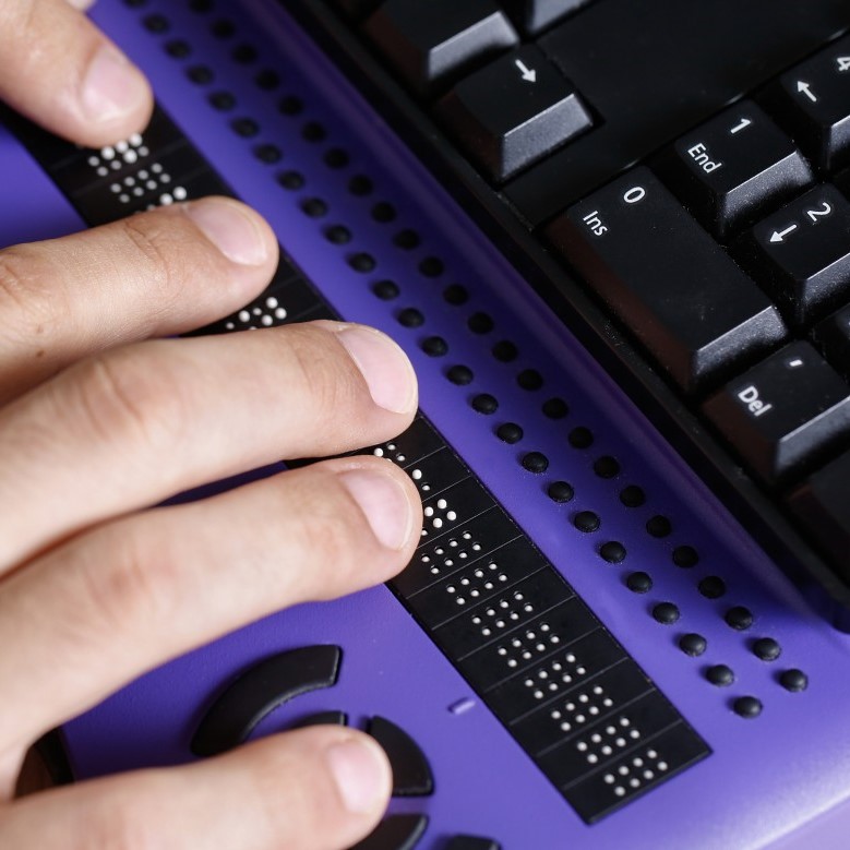 refreshable braille keyboard (photo shows fingers on the i/o controls, and the edge of a computer keyboard positioned on top)