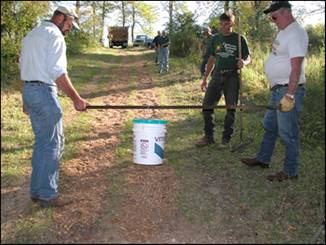 Figure 10---Application of Vitri-Turf to bridle trail by drip-bucket method. Holes drilled in bottom of 19-L (5-gal) container allowed uniform application over 0.4- by 20-m (1.3- by 66-ft) trail.