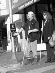black and white photo of two cane users at crosswalk