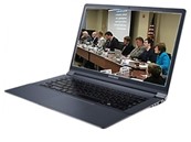 Opened laptop with an image of a Board meeting on the screen. A row of nine people sit at a conference table in front of a projector screen.