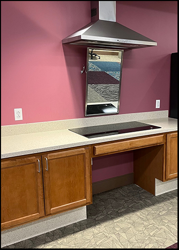 Accessible stovetop with knee and toe clearance and adjustable mirror on backwall at Inglis community center.